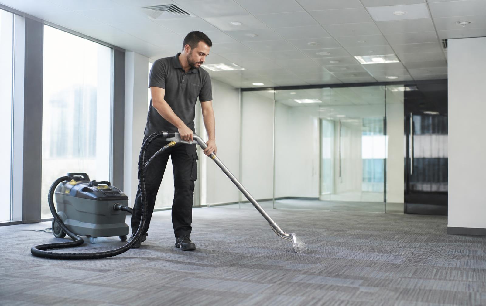 Operator cleaning commercial carpet in an empty office