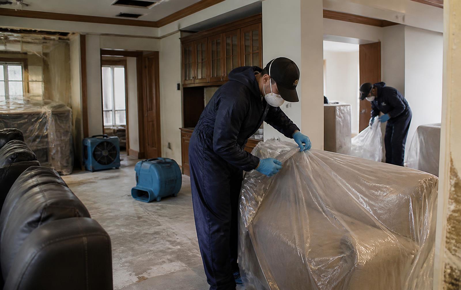 Worker wrapping furniture in plastic sheeting during an insurance contents pack-out